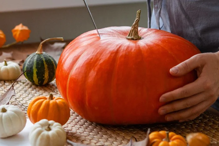 Person schnitzt Kürbis mit Messer